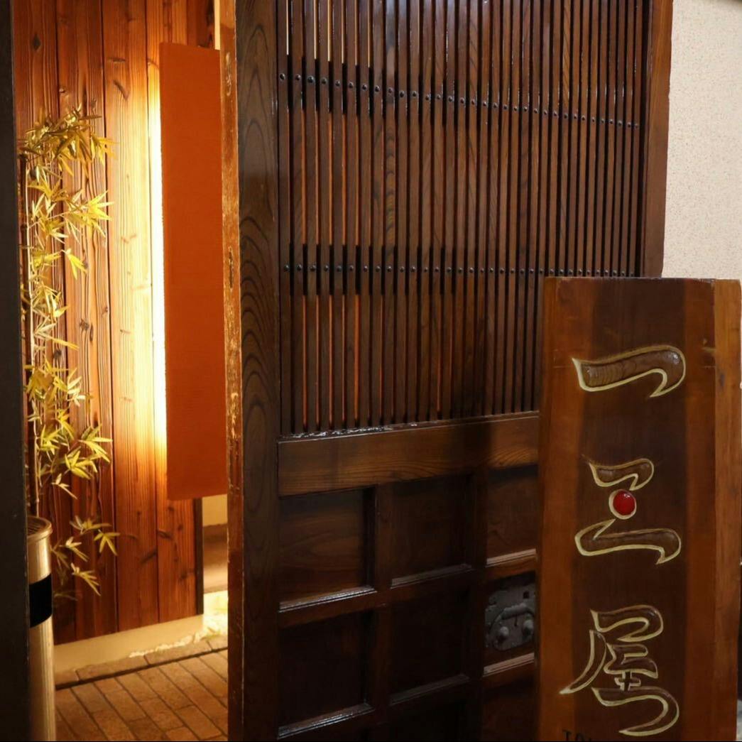 格子戸の脇に立つ木の看板。「一三屋」の三に赤い点